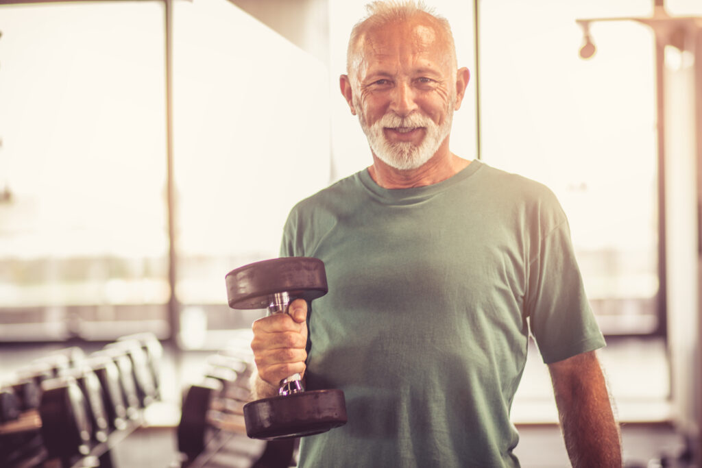 Smiling,Senior,Man,With,Weight,At,Gym.,Looking,At,Camera.
